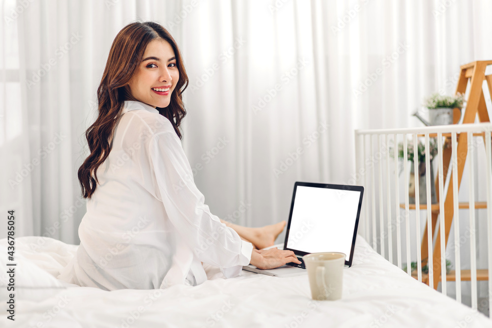 Young smiling happy beautiful asian woman relaxing using laptop computer in the room at home.Young creative girl working and typing on keyboard.work from home concept Young smiling happy beautiful asian woman relaxing using laptop computer in the room at home.Young creative girl working and typing on keyboard.work from home concept