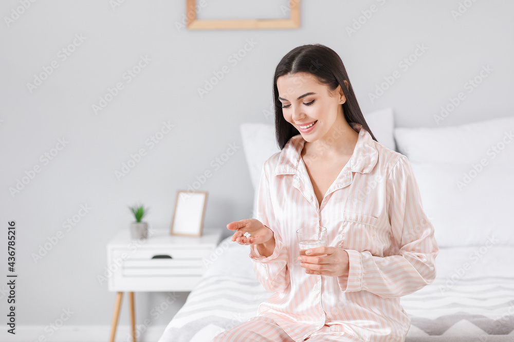 Beautiful young woman taking pills in bedroom Beautiful young woman taking pills in bedroom