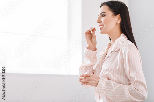 Beautiful young woman taking pills at home