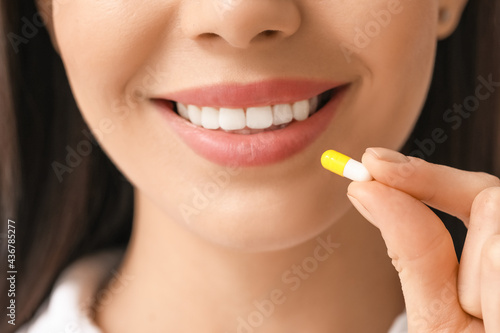 Beautiful young woman taking pills  closeup