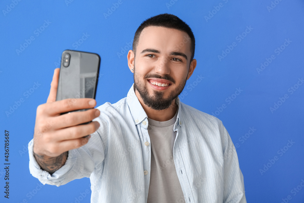 Handsome young man taking selfie on color background Handsome young man taking selfie on color background