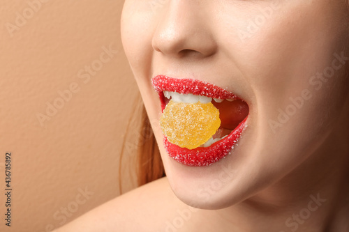 Beautiful young woman with sugar lips eating jelly candy  closeup