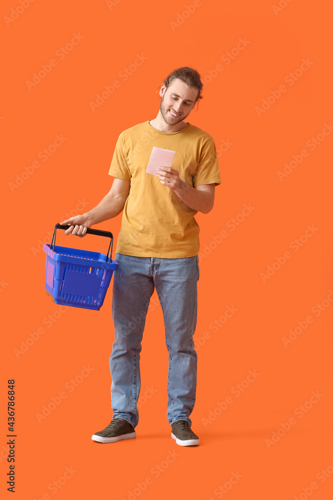 Young man with empty shopping basket and list of products on color background Young man with empty shopping basket and list of products on color background