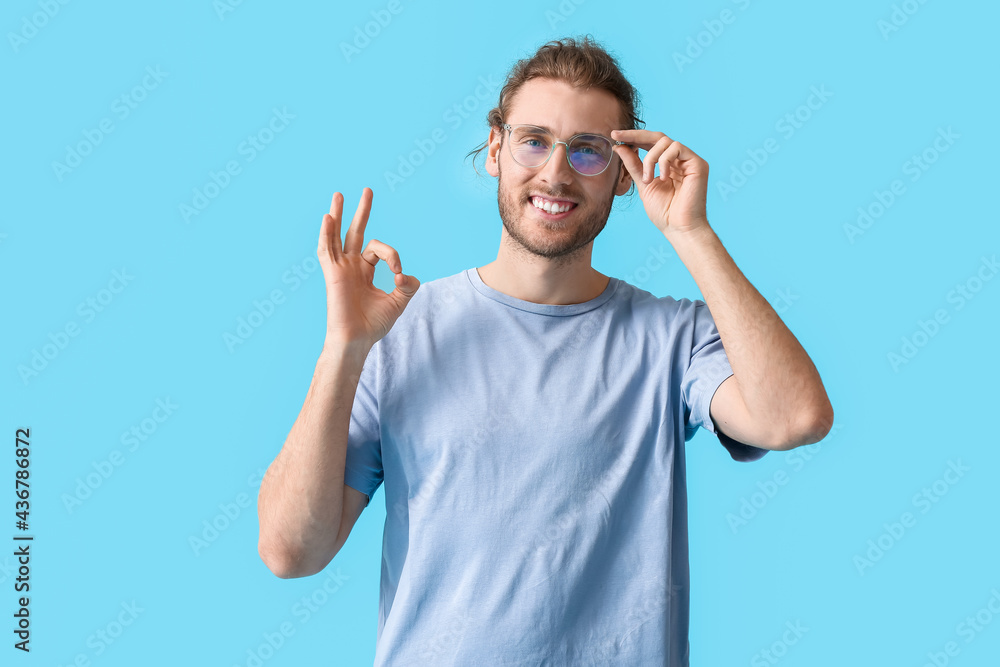Young man wearing eyeglasses and showing OK on color background Young man wearing eyeglasses and showing OK on color background