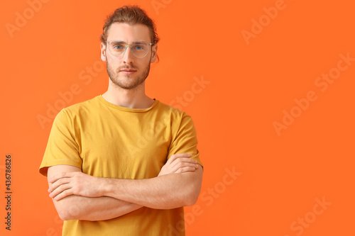 Young man wearing eyeglasses on color background