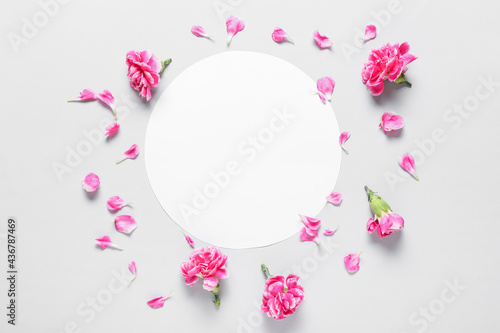 Beautiful carnation flowers and blank card on light background © Pixel-Shot