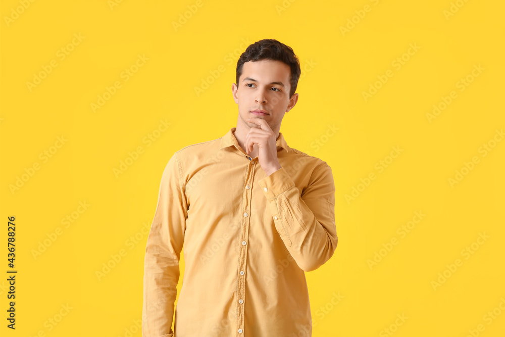Fototapeta premium Thoughtful young man on yellow background