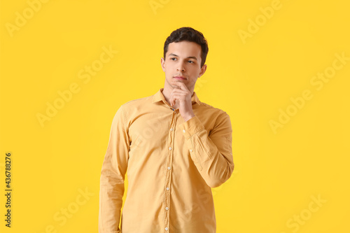 Thoughtful young man on yellow background