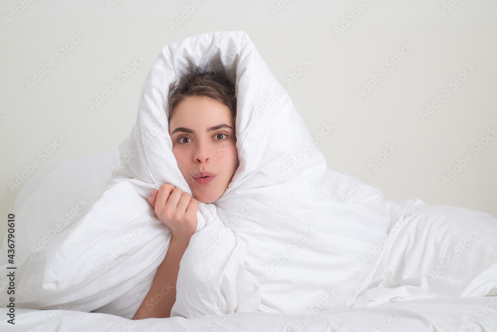 Funny woman wrapped in soft blanket sitting on bed. Smiling girl sitting in bed and smiling at home. Funny woman wrapped in soft blanket sitting on bed. Smiling girl sitting in bed and smiling at home.