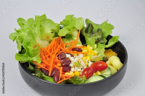Mixed vegetable salad on white plate on white background