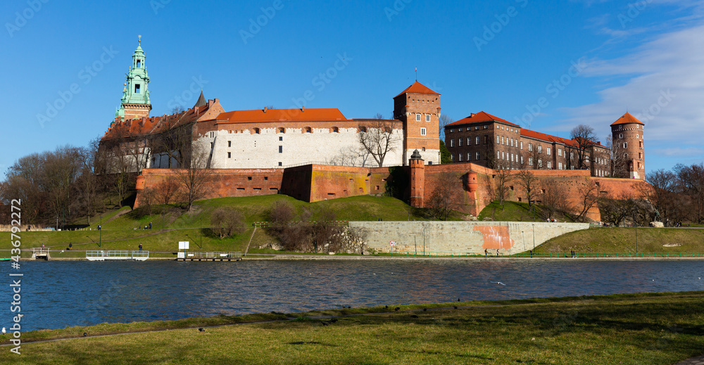 View across Vistula River to Wawel Hill with fortified Castle complex and belfry of Cathedral of Saints Stanislaus and Wenceslaus on sunny spring day, Krakow, Poland..