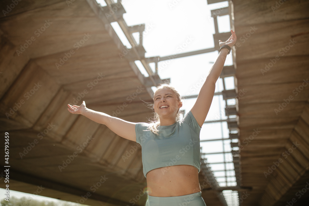 Excited attractive young woman in sportswear enjoying after running outside.