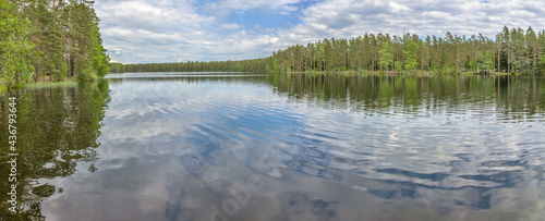 blue sky and clouds reflect in small forest lake