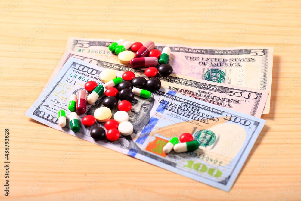 Pharmacy background. Pills on a banknote isolated on a white background. Different types of capsules on dollars banknote. Pharmacy background. Pills on a banknote isolated on a white background. Different types of capsules on dollars banknote.