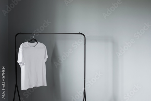 white t-shirt on black hanger against gray wall