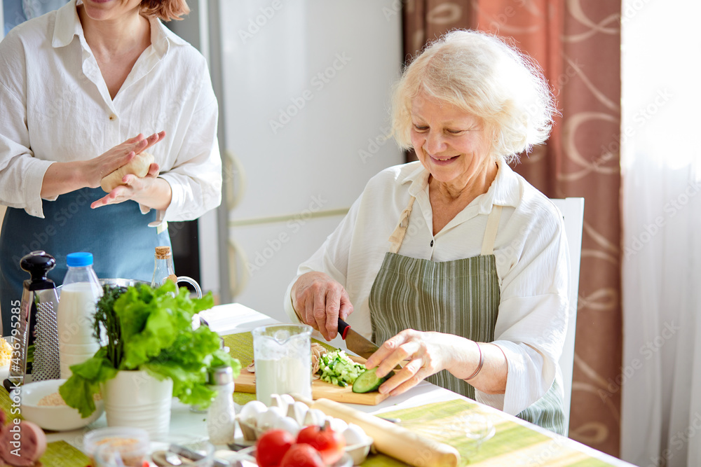 Happy weekends at home. Senior woman preparing food for family at kitchen, wearing apron, retired lady enjoy cooking, 60-70 years old female using cutting board while cooking, portrait Happy weekends at home. Senior woman preparing food for family at kitchen, wearing apron, retired lady enjoy cooking, 60-70 years old female using cutting board while cooking, portrait