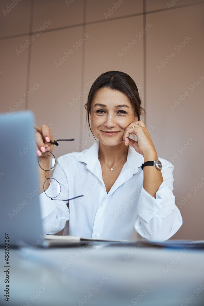 Charming businesswoman sitting at the table in office Charming businesswoman sitting at the table in office