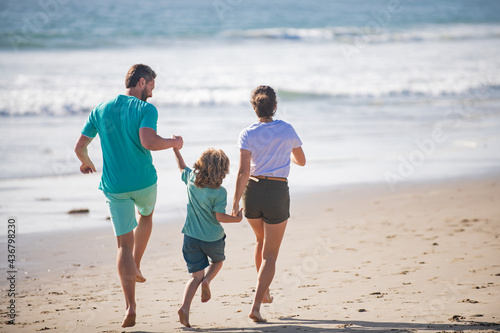 Happy young family run and jump on summer beach. Child with parents running and jumping. Weekend family concept.