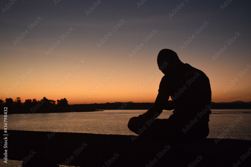 silhouette of a person sitting on a pier