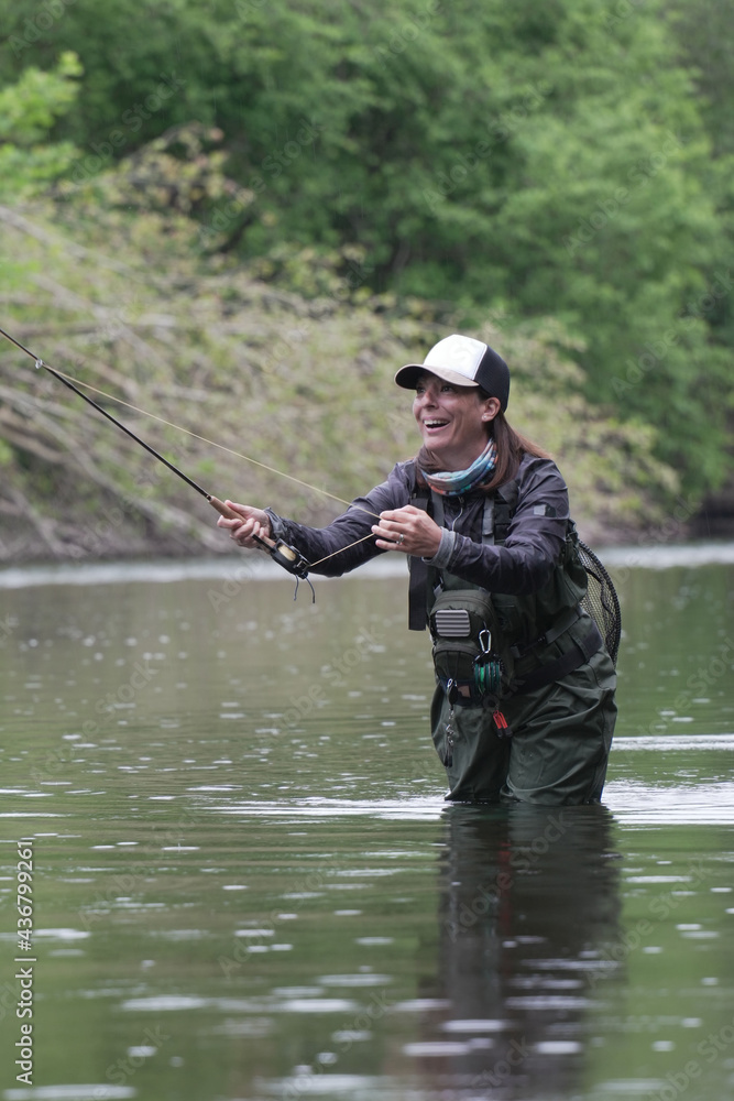 young woman fly fishing for trout in a clear river young woman fly fishing for trout in a clear river
