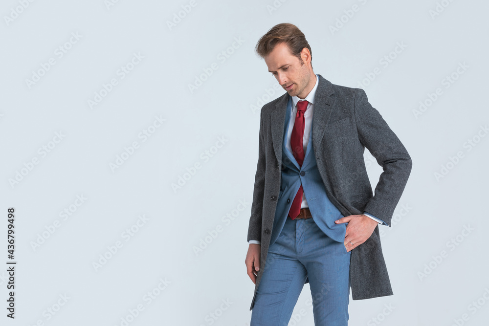 dramatic businessman looking down while sticking one hand in pocket