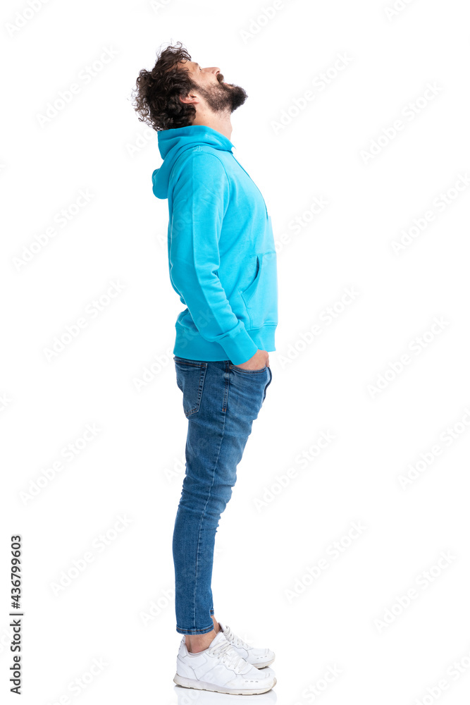 side view of curly bearded guy holding hands in pockets and looking up side view of curly bearded guy holding hands in pockets and looking up