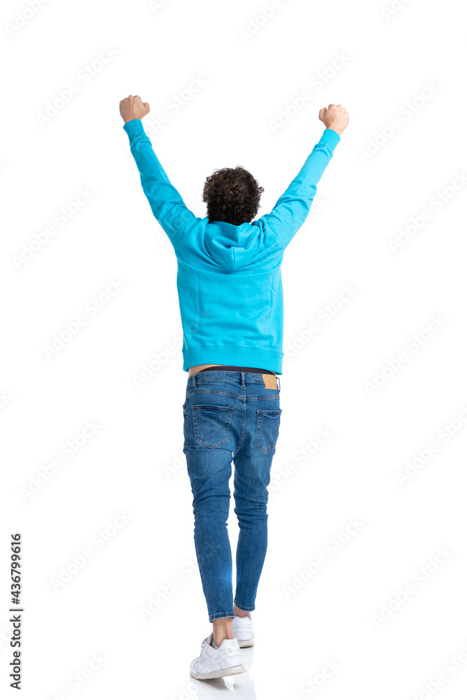 back view of curly man holding arms in the air and cheering back view of curly man holding arms in the air and cheering