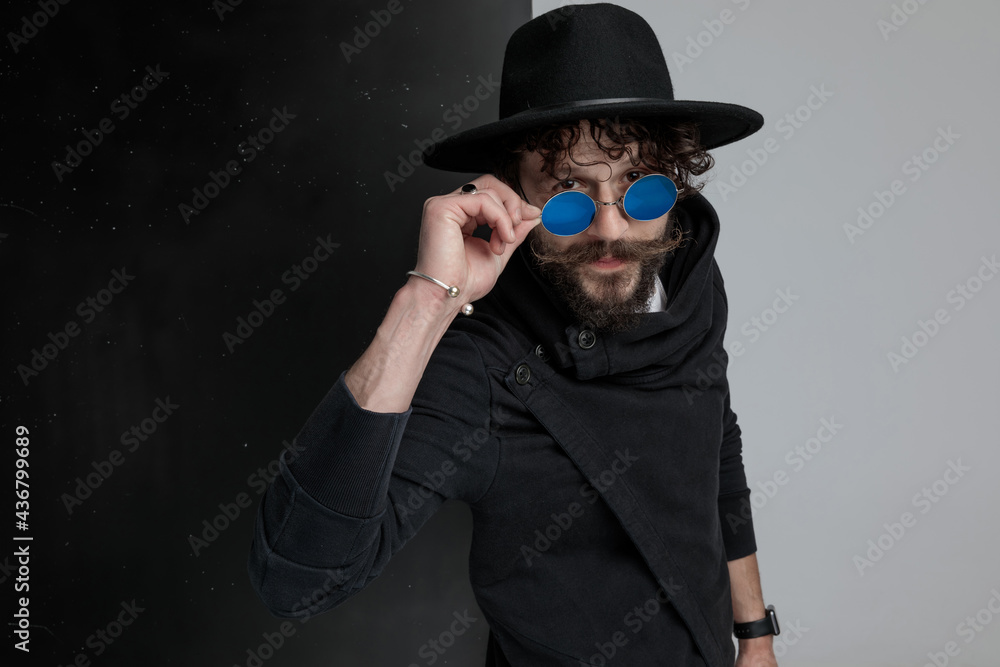 attractive bearded man with black hat looking over glasses