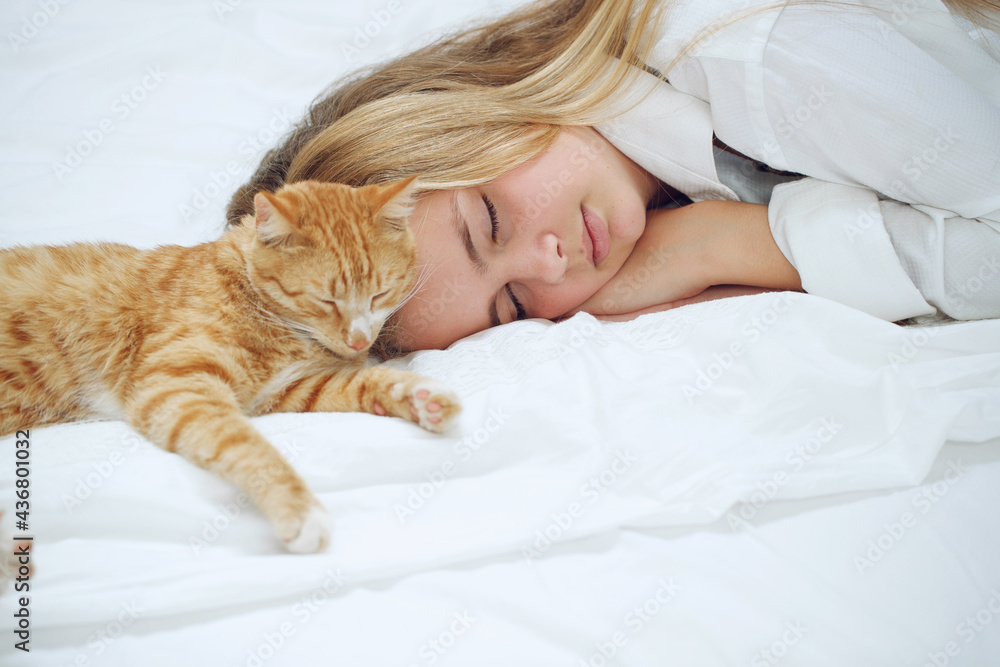 The girl is resting on the bed with her ginger kitten. A child with an animal. High quality photo. The girl is resting on the bed with her ginger kitten. A child with an animal. High quality photo.