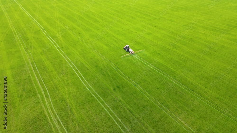 Tractor spraying big endless green field. Aerial view of farming machinery plowing and spraying on field. Concept of work in agronomic farm for making business and having profit from production Tractor spraying big endless green field. Aerial view of farming machinery plowing and spraying on field. Concept of work in agronomic farm for making business and having profit from production