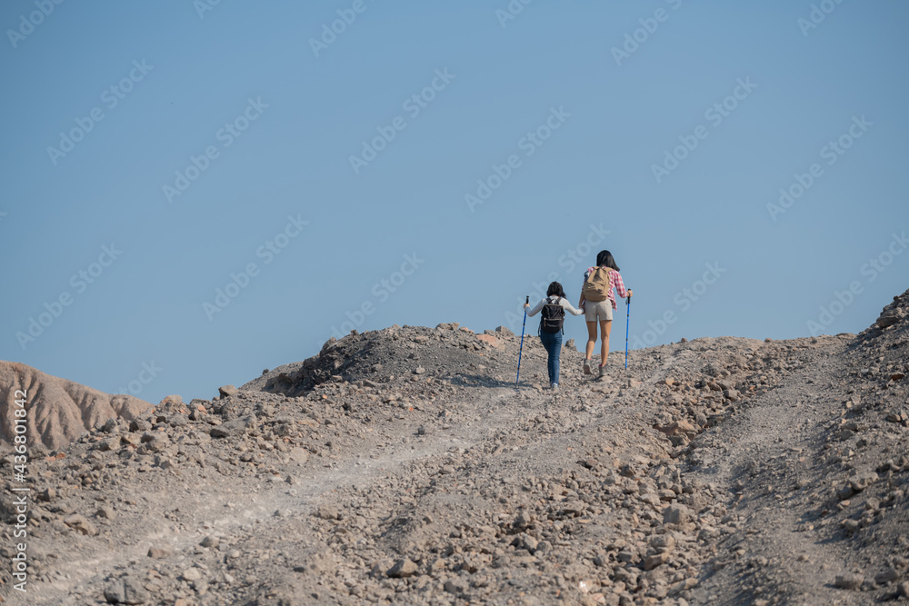 family travel- hikers with backpack looking at mountains view, mother with child at the day time, little girl with mother trekking on red trail, Concept of friendly family.