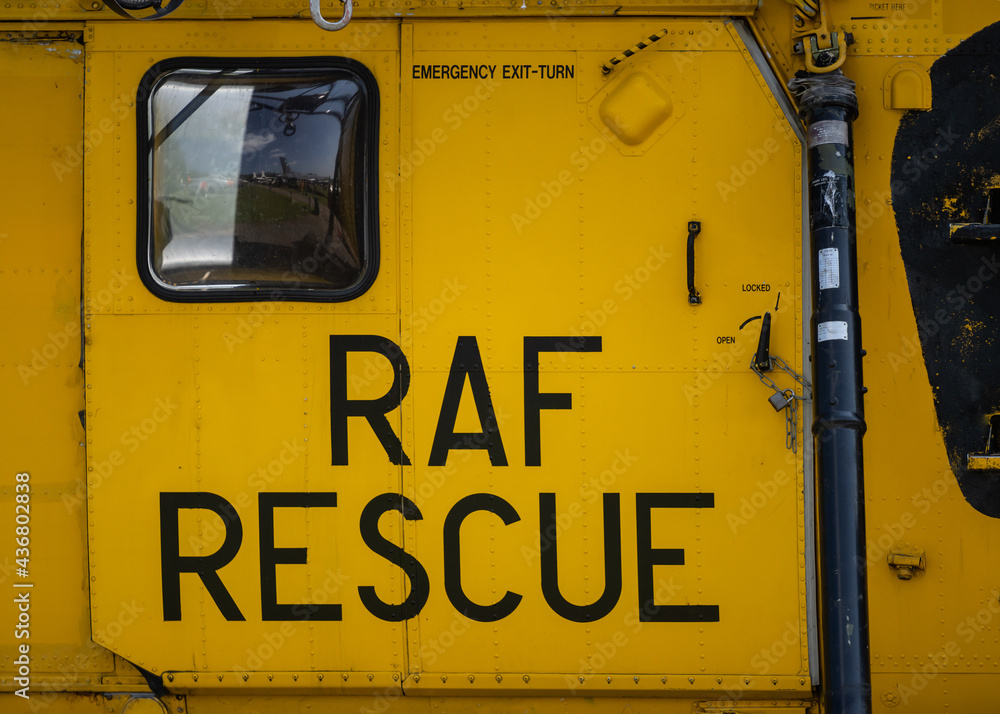 Yellow RAF Royal Air Force rescue military Sea King helicopter writing text on sliding metal aircraft door above winch.