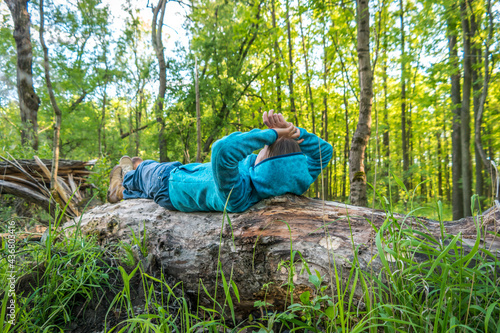 woman relaxes on a fallen tree in the forest
