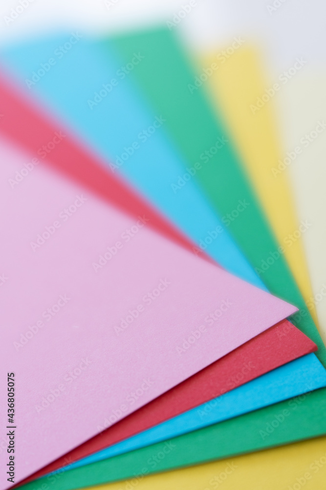 Colorful paper sheets shaped as a fan. Vertical photo. Copy space. Sharp and blurred areas. Colorful paper sheets shaped as a fan. Vertical photo. Copy space. Sharp and blurred areas.