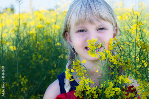 Little blonde girl is playing in a meadow flower