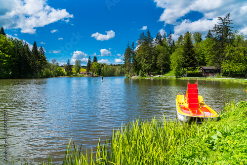 Germany, Colorful pedal boat on water surface of  beautiful ebnisee lake near kaisersbach surrounded by green trees of forest with sunshine in summer season photo