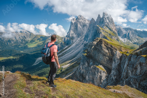 A man with backpack enjoy landscape of Seceda peak in Dolomites Alps, Odle mountain range, South Tyrol, Italy, Europe. Travel vacation concept