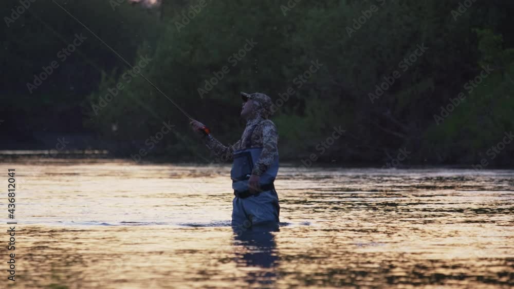 Fly fishing. Fisherman casts fly on the river at sunset. Caucasian amateur angler fishing on the river on fly during warm summer evening Fly fishing. Fisherman casts fly on the river at sunset. Caucasian amateur angler fishing on the river on fly during warm summer evening