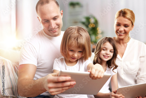 family, technology and people - happy father, mother and two daughters with tablet pc computers at home