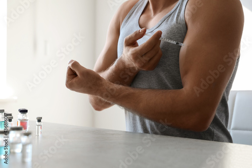 Plakat Athletic man injecting himself at table indoors, closeup. Doping concept
