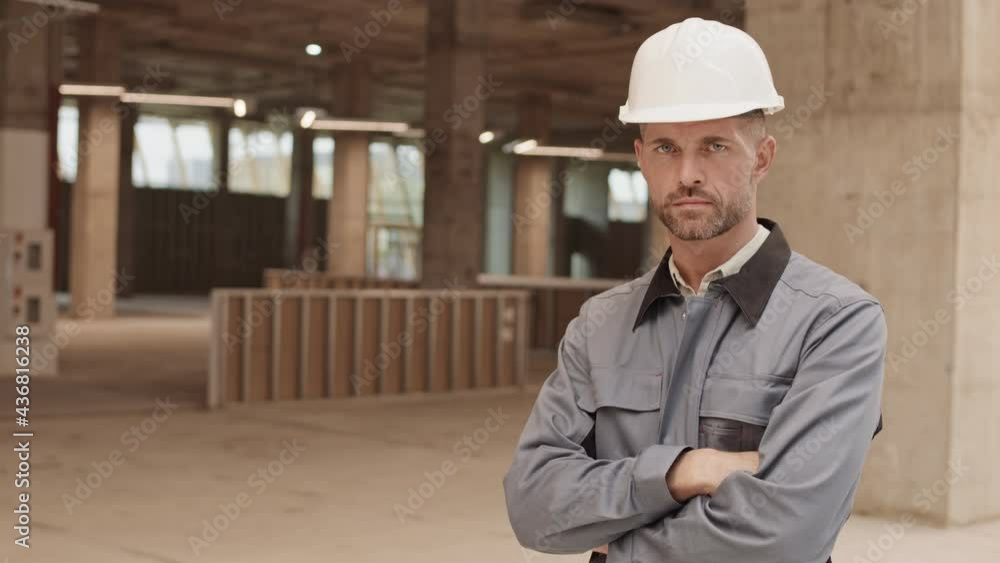 Waist-up POV of confident Caucasian male construction worker standing in building, crossing arms on chest and looking on camera Waist-up POV of confident Caucasian male construction worker standing in building, crossing arms on chest and looking on camera