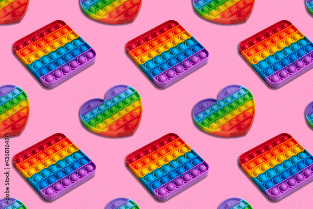 Rainbow heart and square shape isometric pattern of silicon toy for kids. Pop it fidget toy on pastel background. Simple dimple toy on pink pastel background.  - obrazy, fototapety, plakaty 
