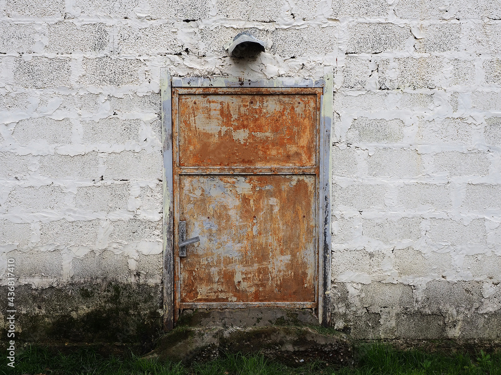 Small rusty peeling basement door in an unplastered foam block wall Small rusty peeling basement door in an unplastered foam block wall