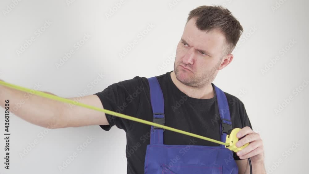 Close-up, a handsome male builder in uniform pulls out of his pocket and looks at his tools Close-up, a handsome male builder in uniform pulls out of his pocket and looks at his tools