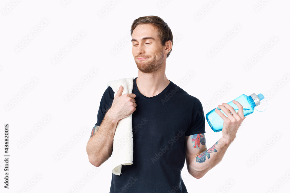 man in a black t-shirt with a bottle of water in his hand and a towel on his shoulder cropped view Copy Space man in a black t-shirt with a bottle of water in his hand and a towel on his shoulder cropped view Copy Space