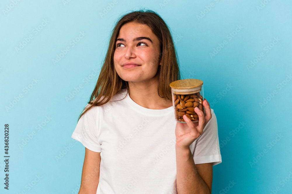 Young caucasian woman holding an almond jar isolated on blue background dreaming of achieving goals and purposes Young caucasian woman holding an almond jar isolated on blue background dreaming of achieving goals and purposes