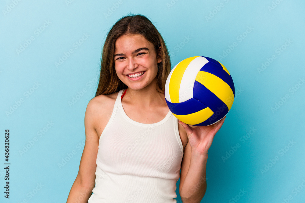 Young caucasian woman playing volleyball isolated on blue background happy, smiling and cheerful.
