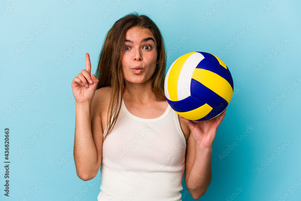 Young caucasian woman playing volleyball isolated on blue background having some great idea, concept of creativity. Young caucasian woman playing volleyball isolated on blue background having some great idea, concept of creativity.