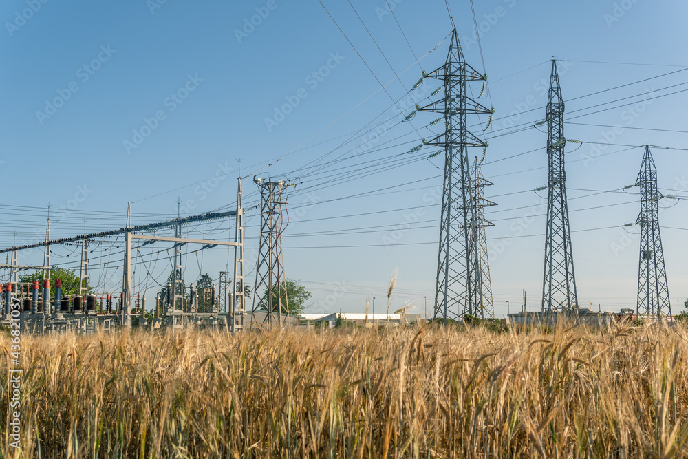 Metallic towers of a power station in the middle of a sunny field Metallic towers of a power station in the middle of a sunny field