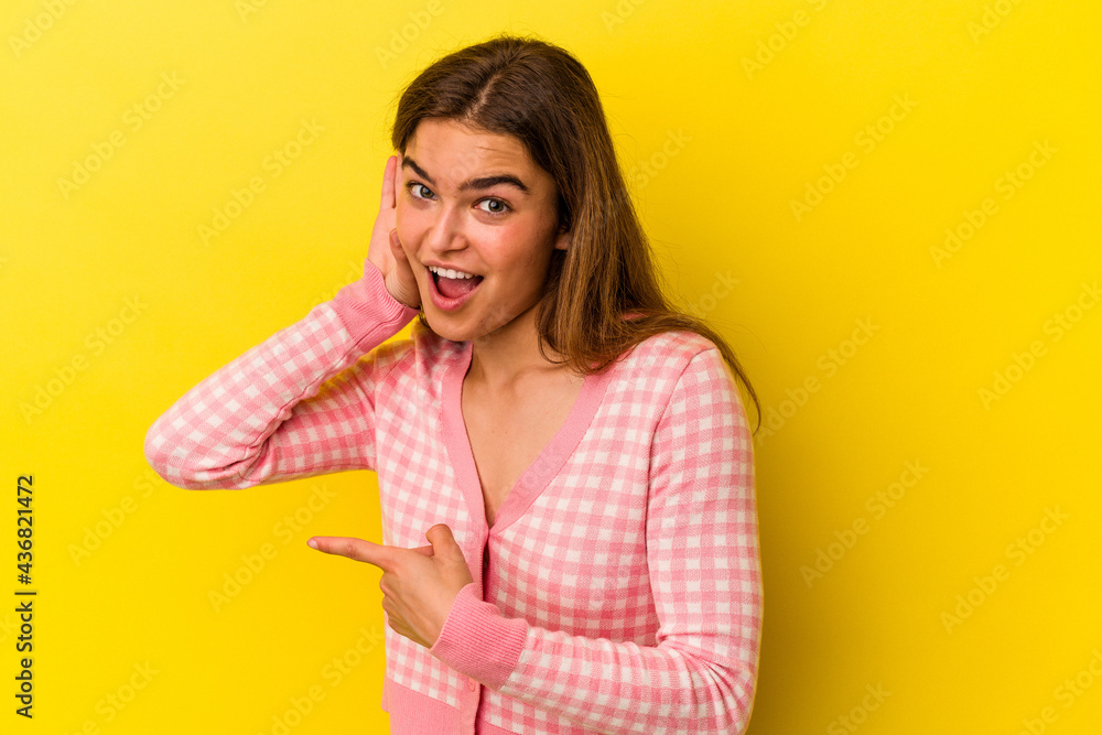 Young caucasian woman isolated on yellow background trying to listening a gossip. Young caucasian woman isolated on yellow background trying to listening a gossip.